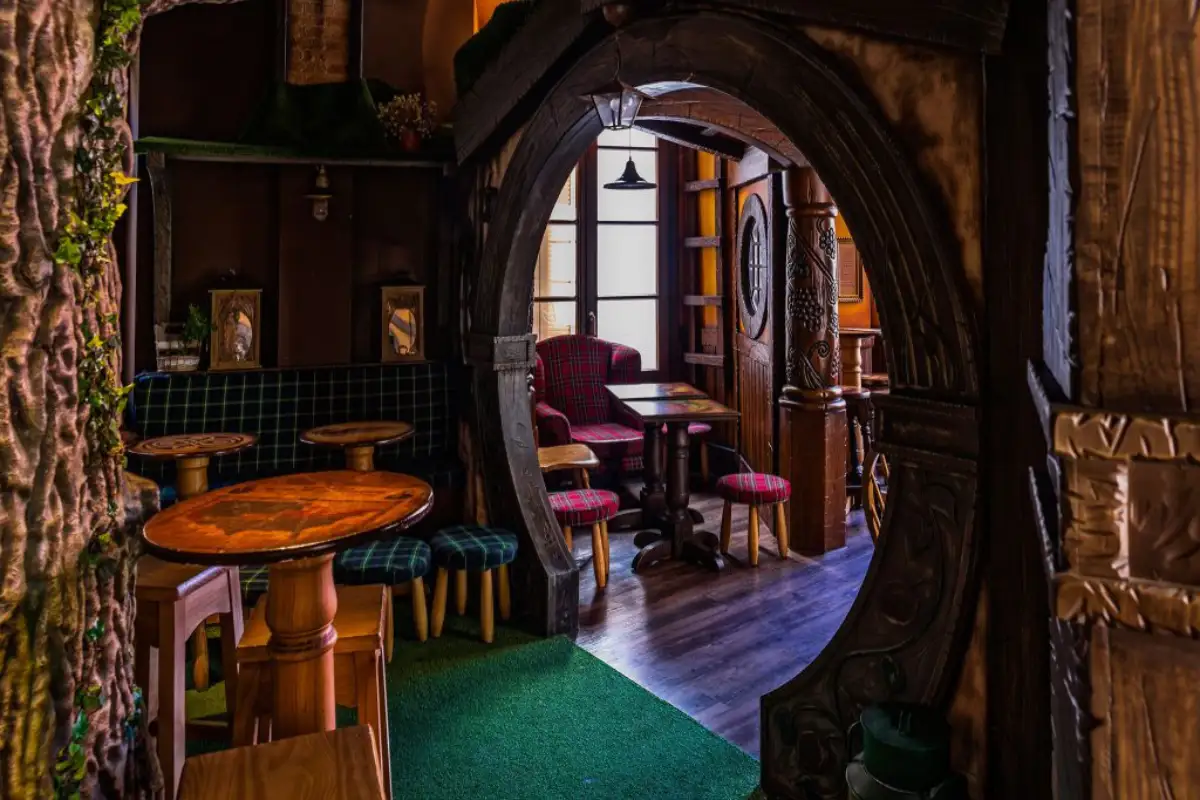 Round hobbit-door entrance with fantasy-themed decor inside Sala Premier bar, Málaga