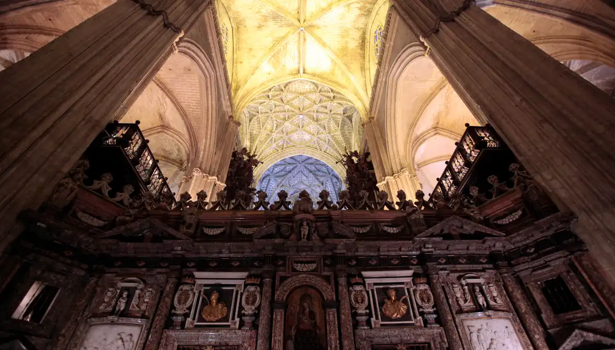 Soaring Gothic vaulted ceiling and golden altarpiece inside Seville Cathedral