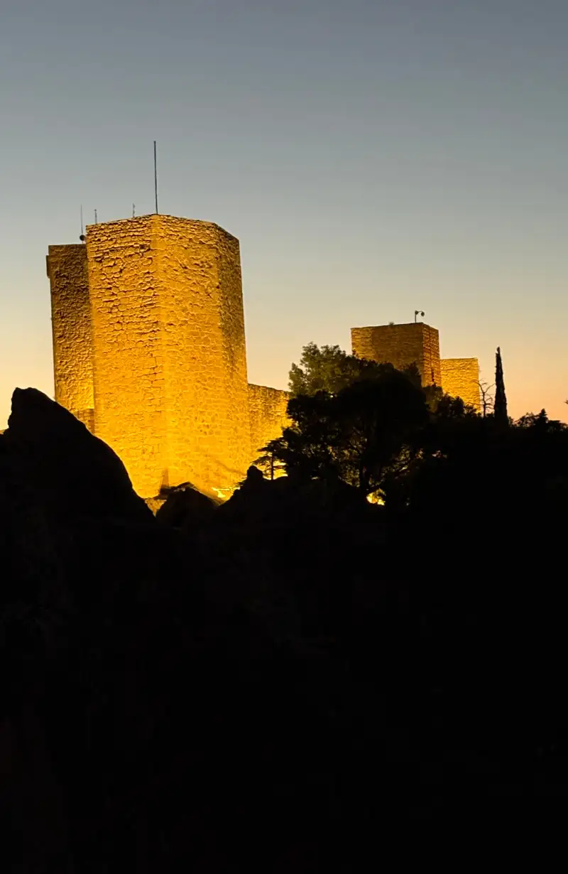 Castillo de Santa Catalina lit up at night against a dusk sky in Jaén
