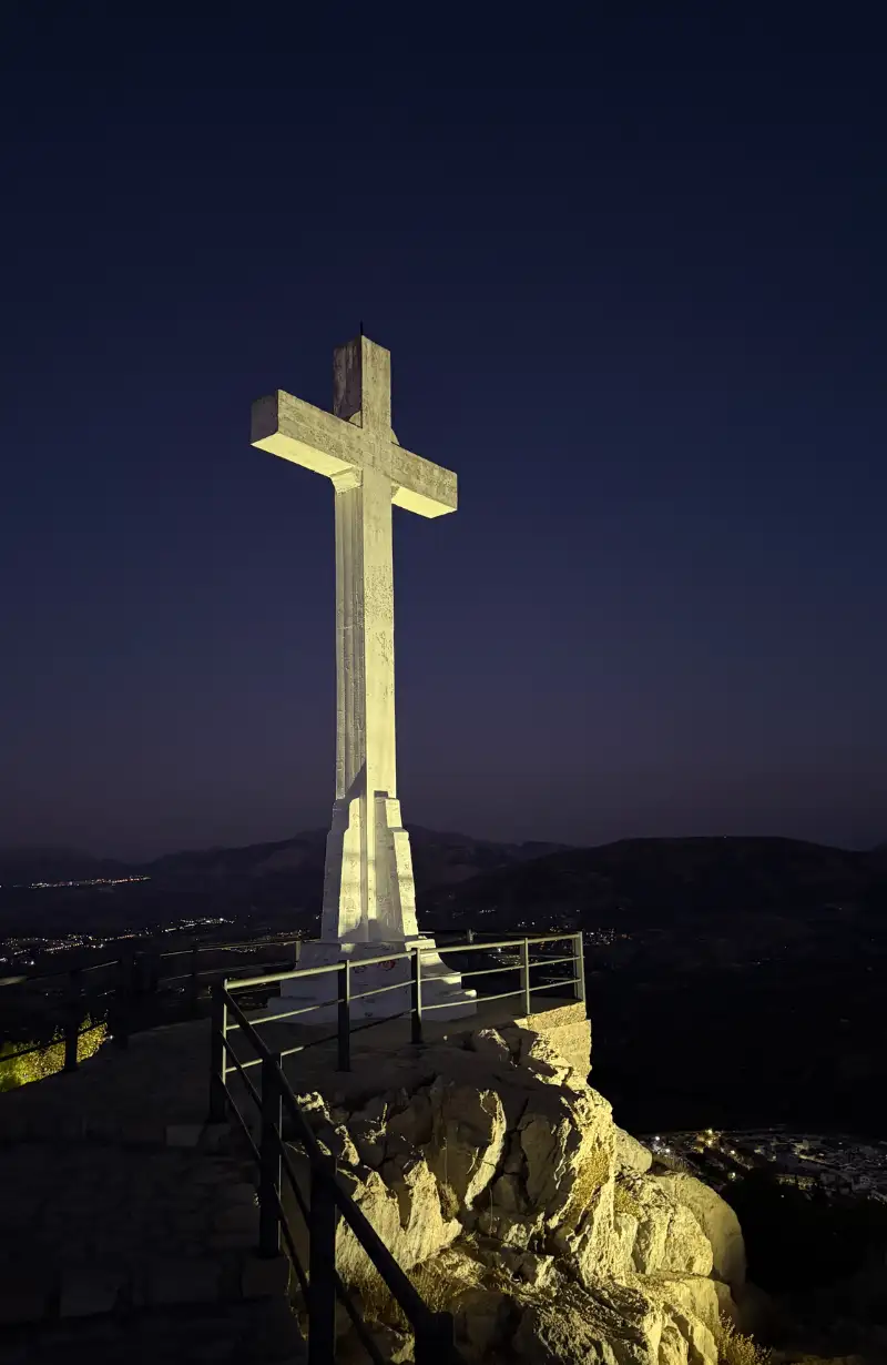 The illuminated cross at the Castillo de Santa Catalina viewpoint at night with the Jaén valley below