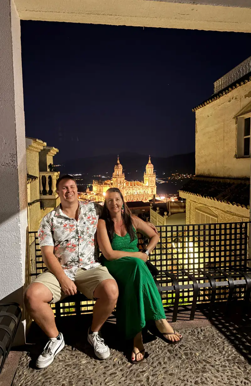 Heidi and Jethro sitting on a terrace at night with Jaén Cathedral illuminated behind them