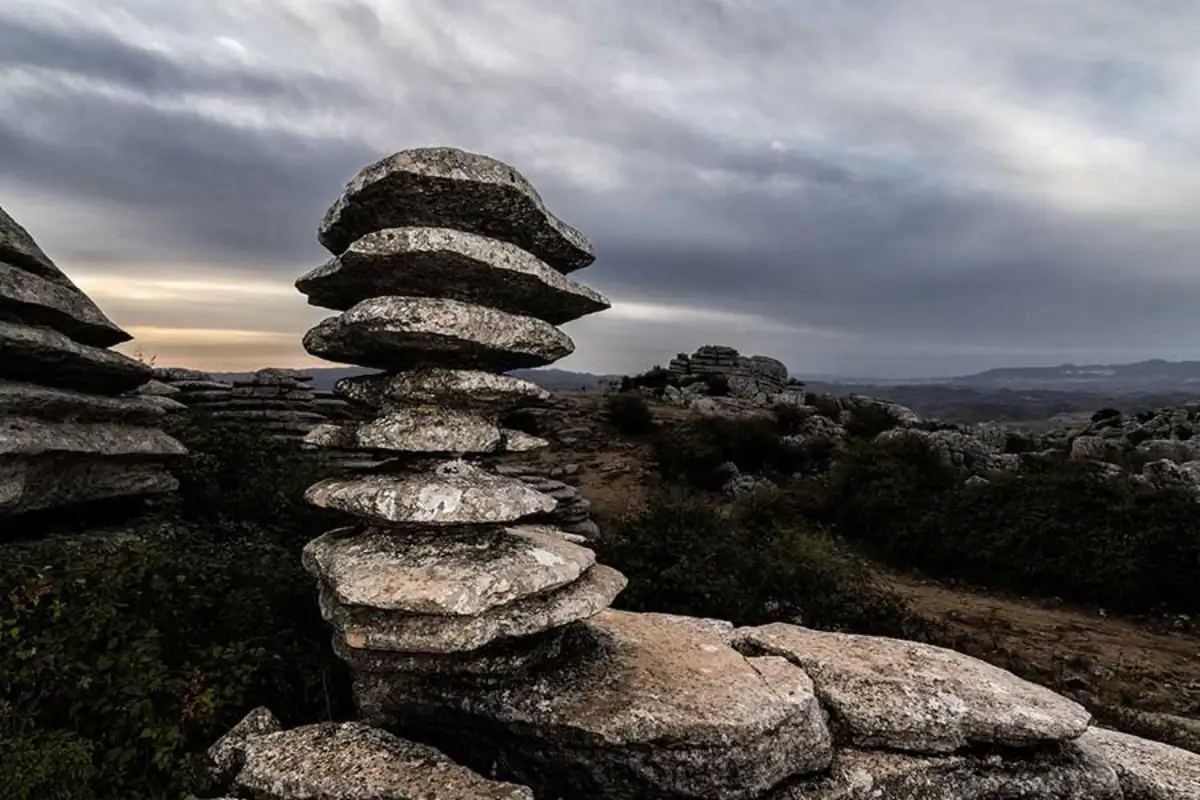 A series of stones stacked on top of each other with the Antequera dolmens behind them.