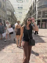 Heidi walking down Calle Larios in Málaga with a black cross-body bag zipped across her front, the crowd behind her