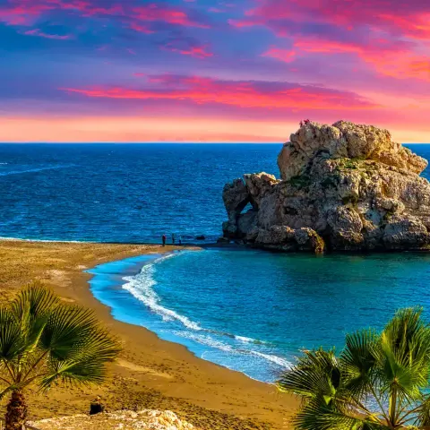 Rock arch on a Málaga beach at sunset