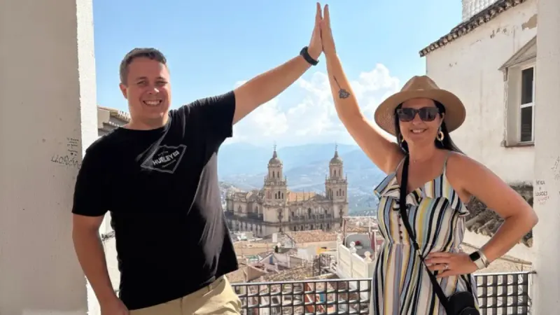Couple high-fiving on a rooftop viewpoint with Jaén Cathedral in the background