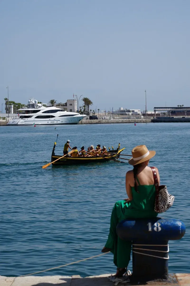 Heidi in a green dress watching a jábega rowing race from the harbour in Málaga