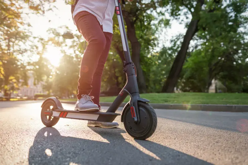 Person riding an electric scooter along a sunny city path in Málaga