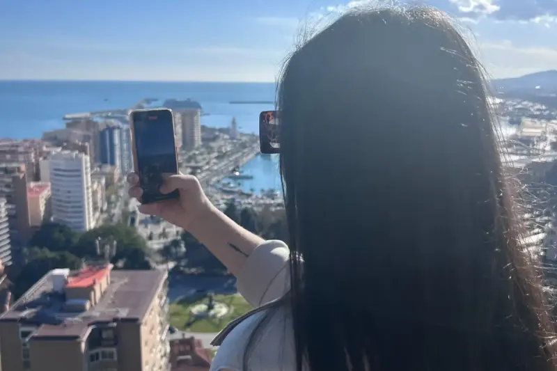 Visitor photographing the panoramic view over Málaga city and port from above