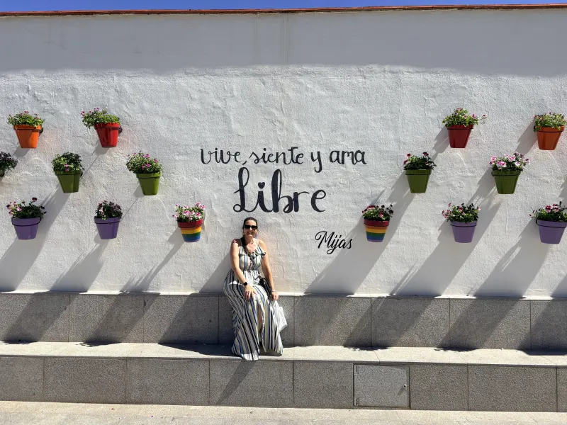 Woman posing in front of the Vive Siente Ama Libre street art mural in Mijas Pueblo