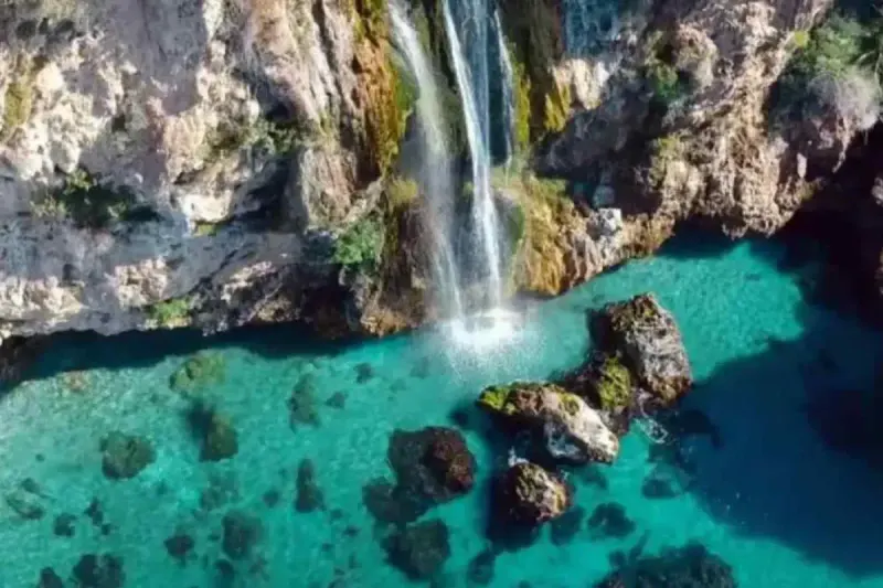 Aerial view of the Maro waterfall cascading onto turquoise rocks near Nerja