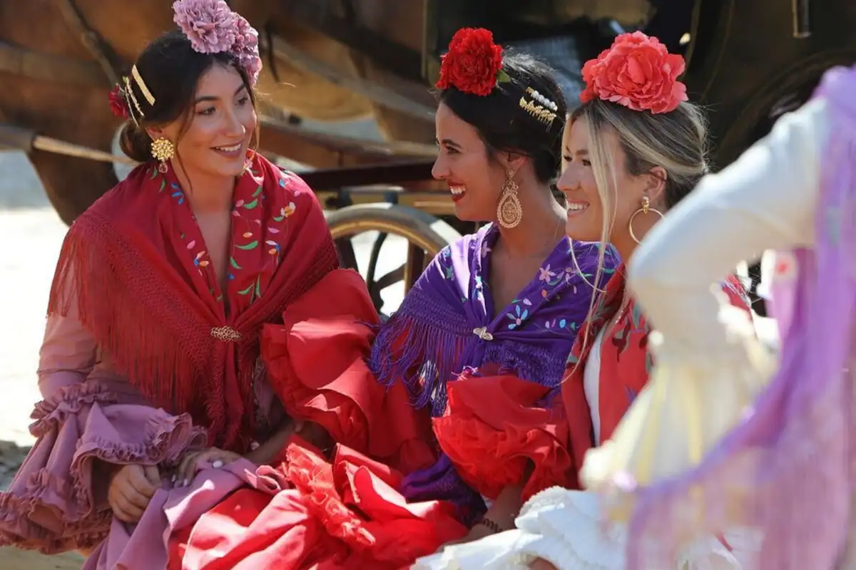Women in flamenco dresses with flowers in their hair at Seville's Feria de Abril