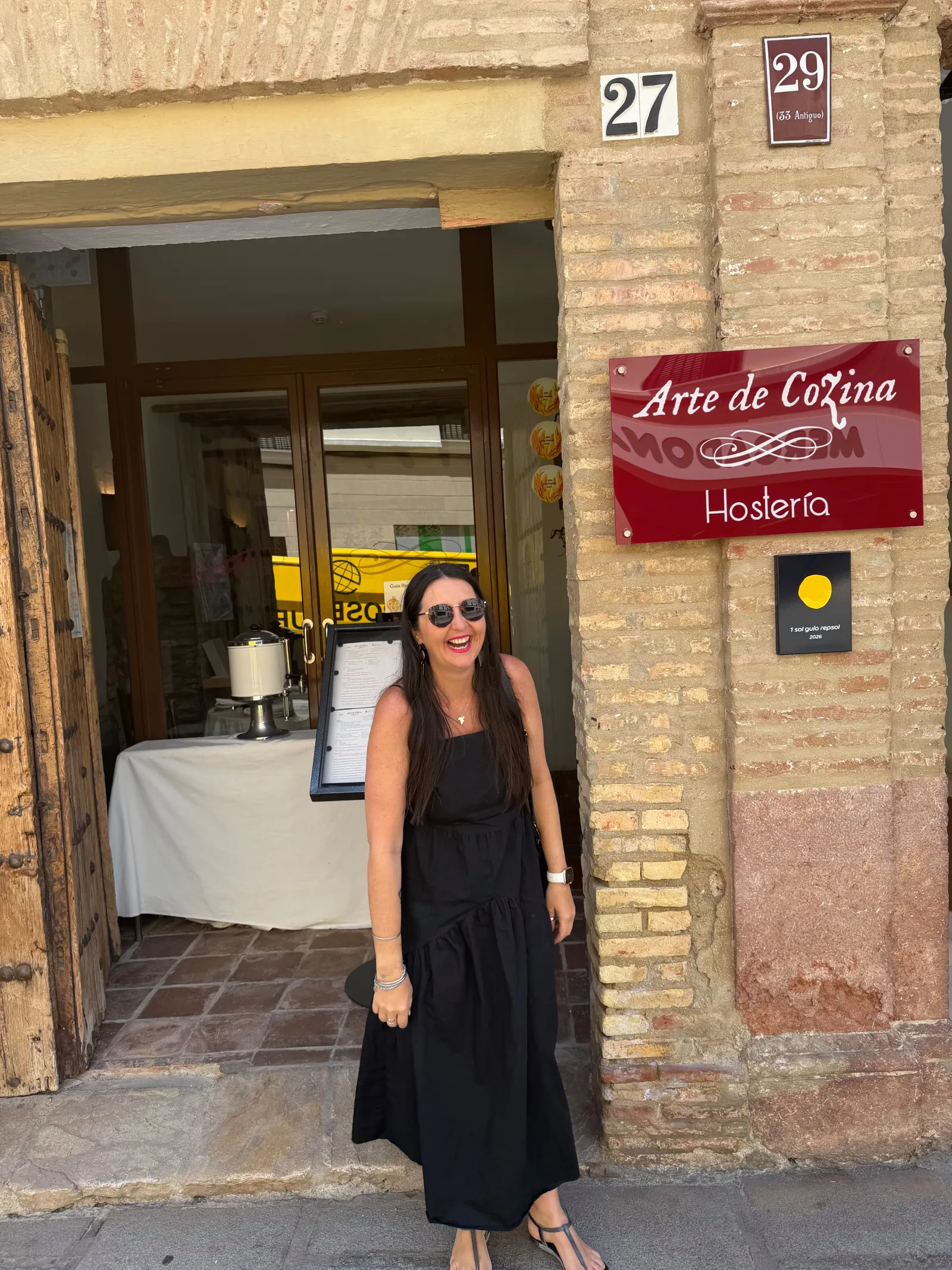 Heidi standing in front of the Arte de Cozina restaurant sign in Antequera