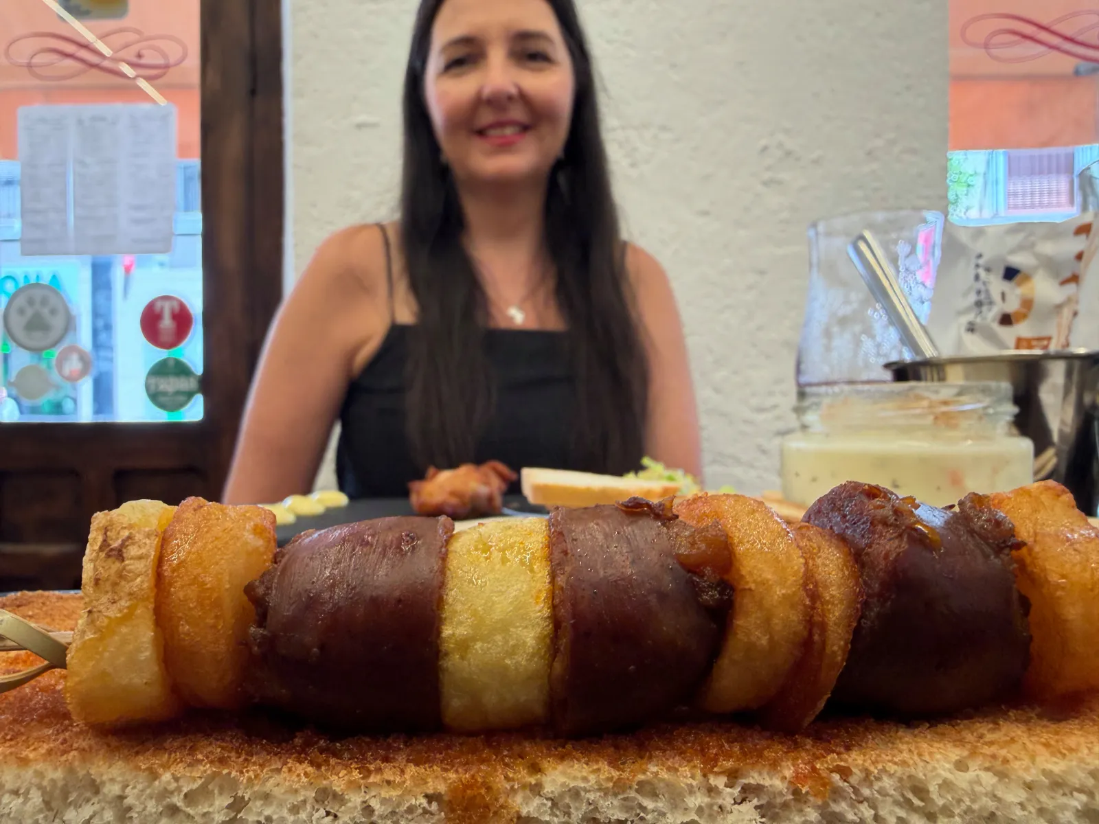 Heidi holding a chorizo skewer tapa at a bar in Antequera