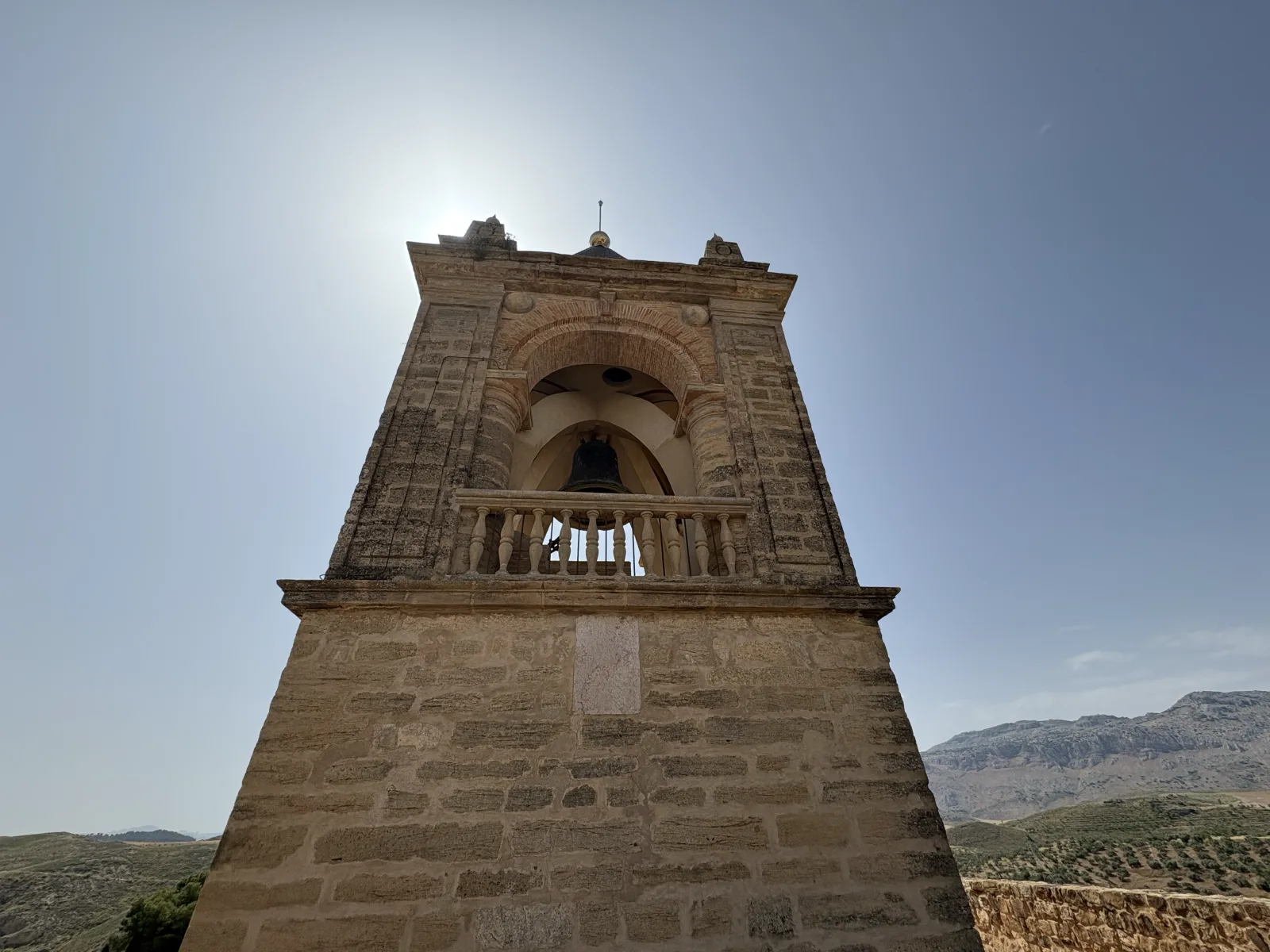 A historic stone bell tower rising above Antequera against the surrounding hills
