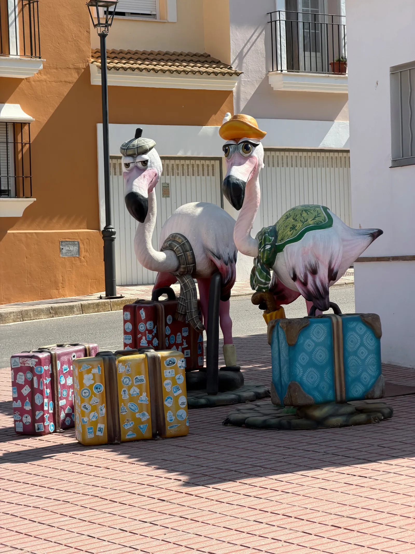 Flamingo sculptures posed as tourists with suitcases in Fuente de Piedra village