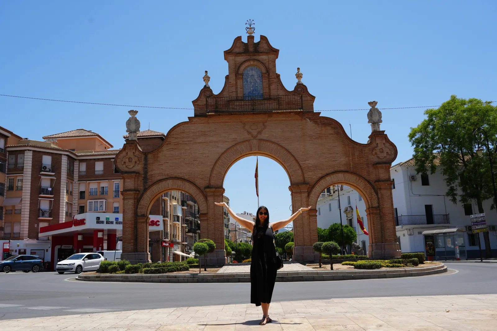 Heidi with arms outstretched in front of the brick Puerta de Estepa gateway in Antequera