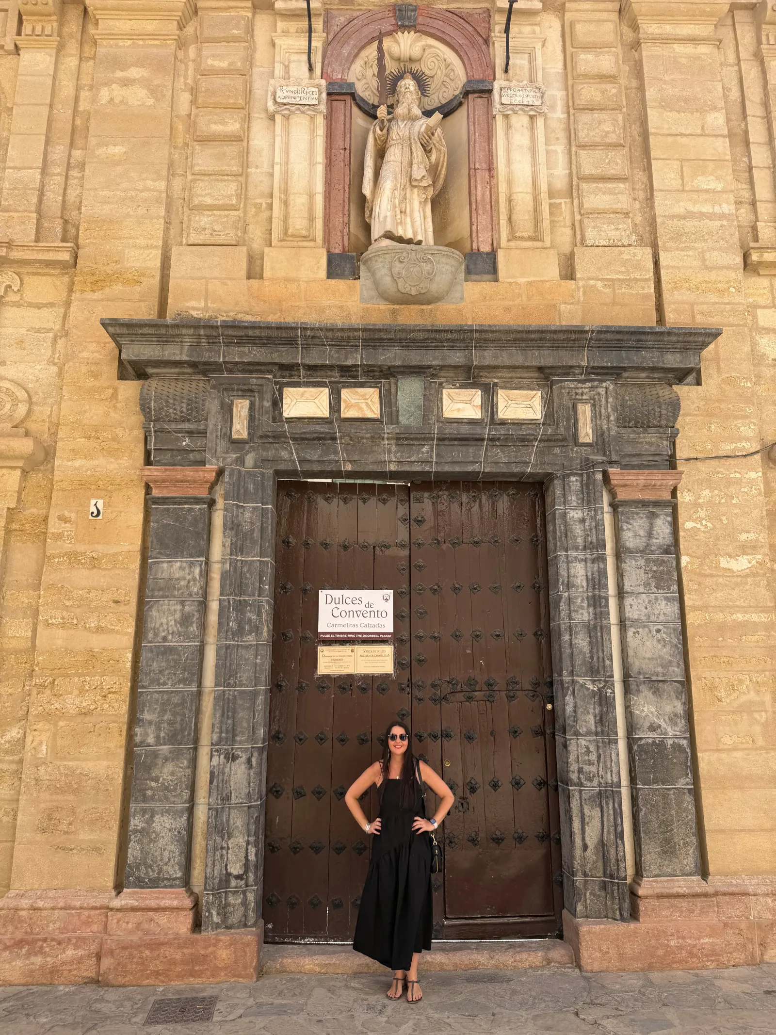 Heidi standing at the large wooden door of a convent in Antequera
