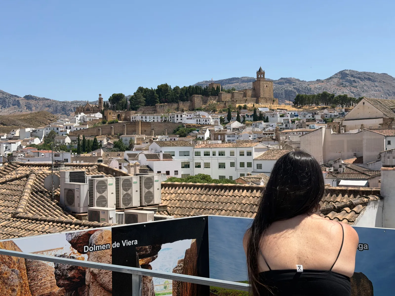 Heidi looking out from a rooftop terrace over Antequera's white town towards the Alcazaba on the hill
