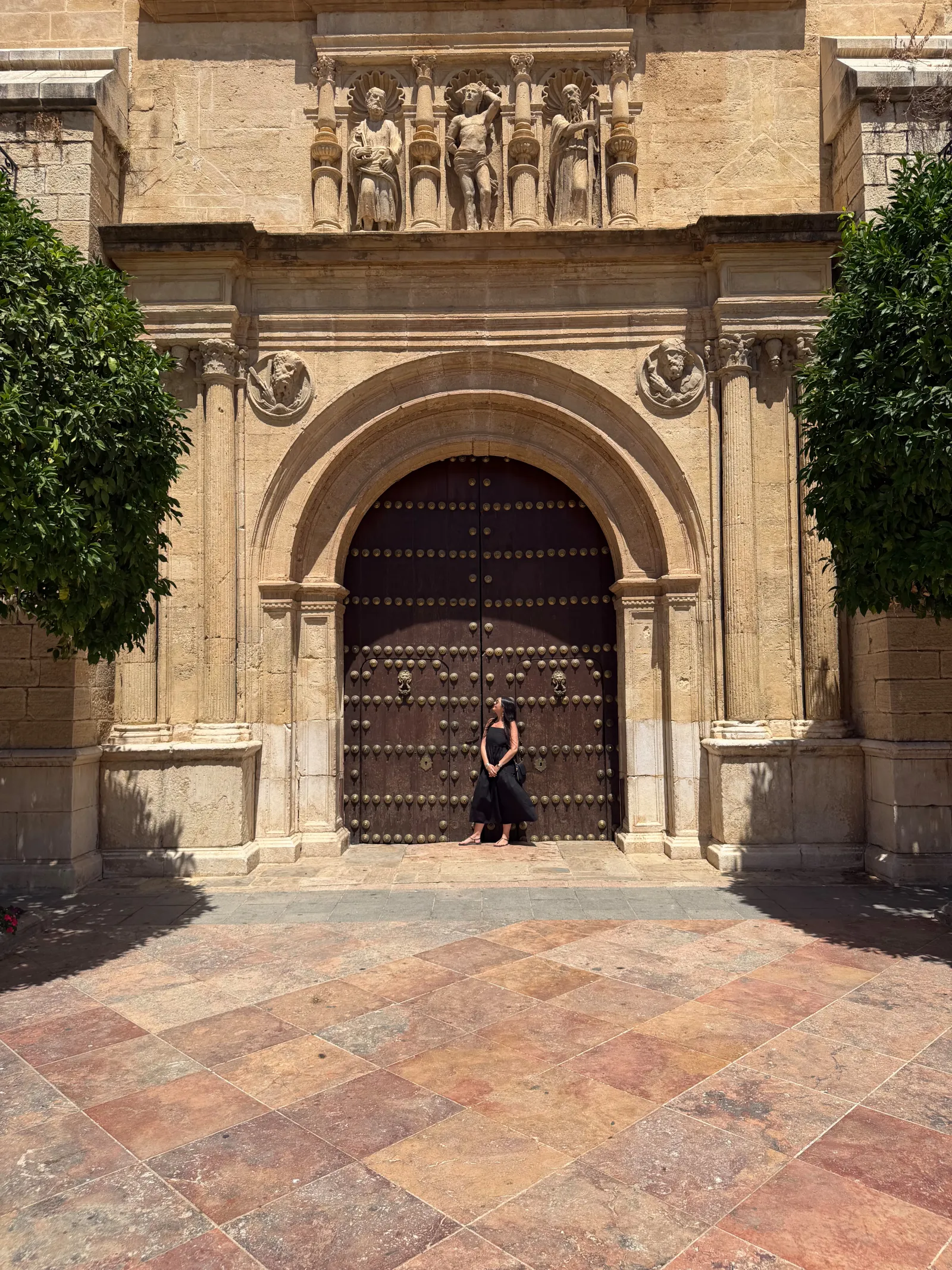 A woman standing in front of a large church door in Antequera.