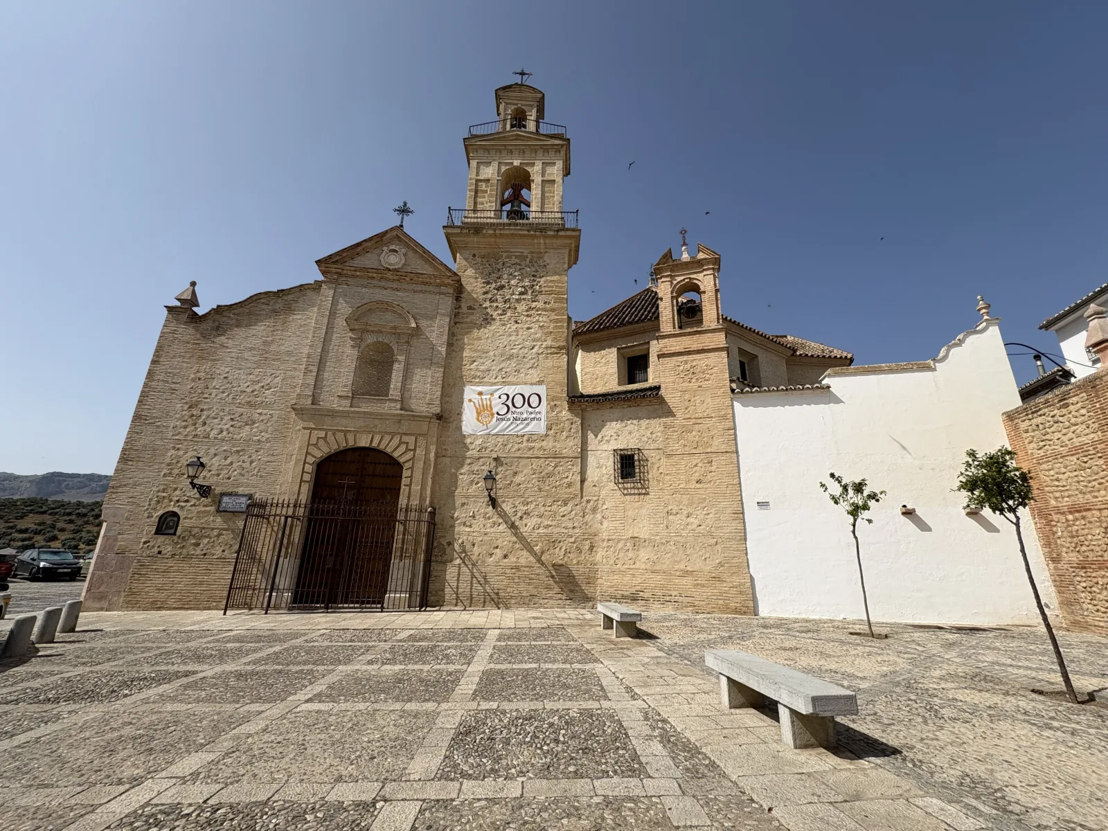 Stone facade and bell tower of the Iglesia de Santa María de Jesús on its plaza in Antequera