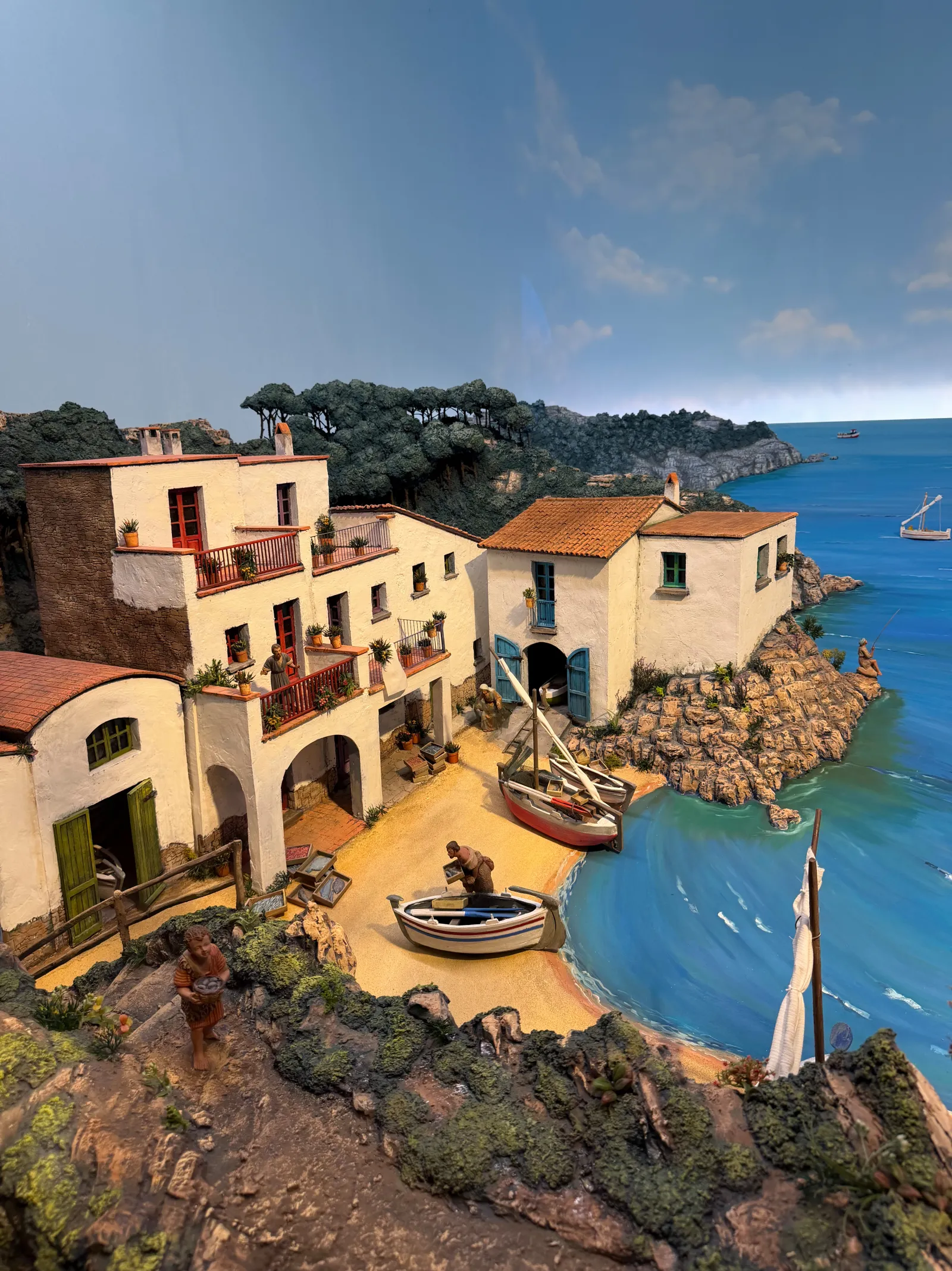 Detailed nativity diorama of a fishing village with boats and a painted sea backdrop