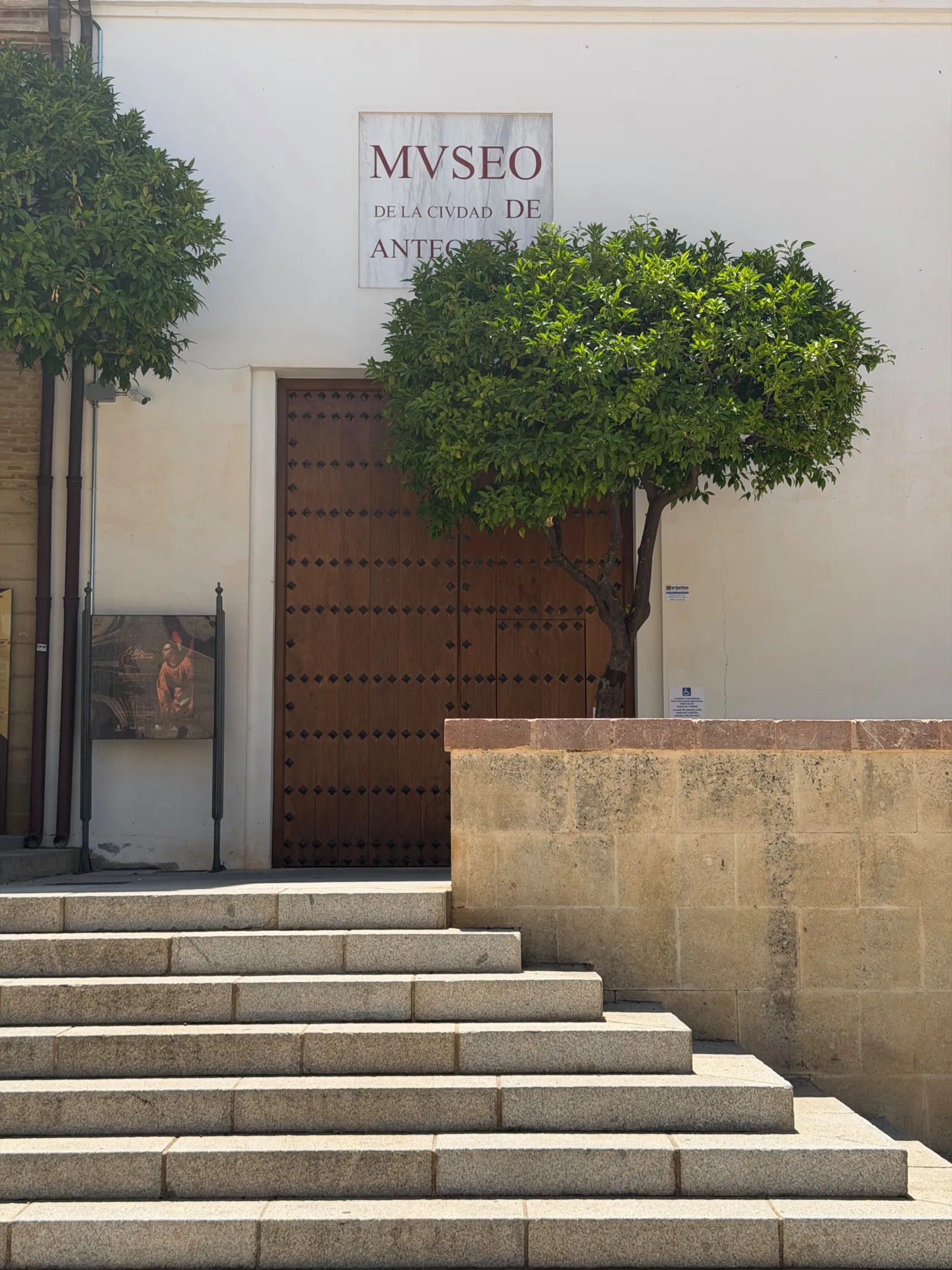 The entrance to the Museo de la Ciudad de Antequera, with its MVSEO sign above a wooden door and stone steps