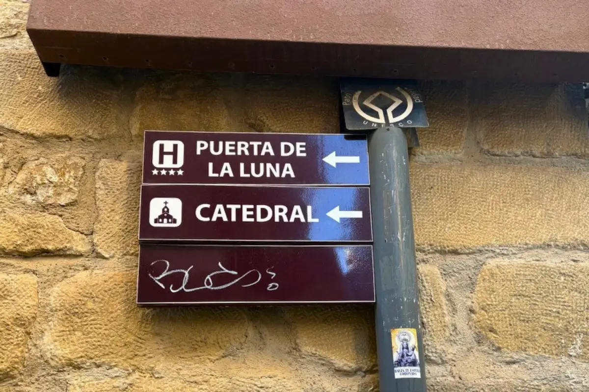 Street signs pointing to Puerta de la Luna hotel and the Cathedral in Baeza, with UNESCO World Heritage logo