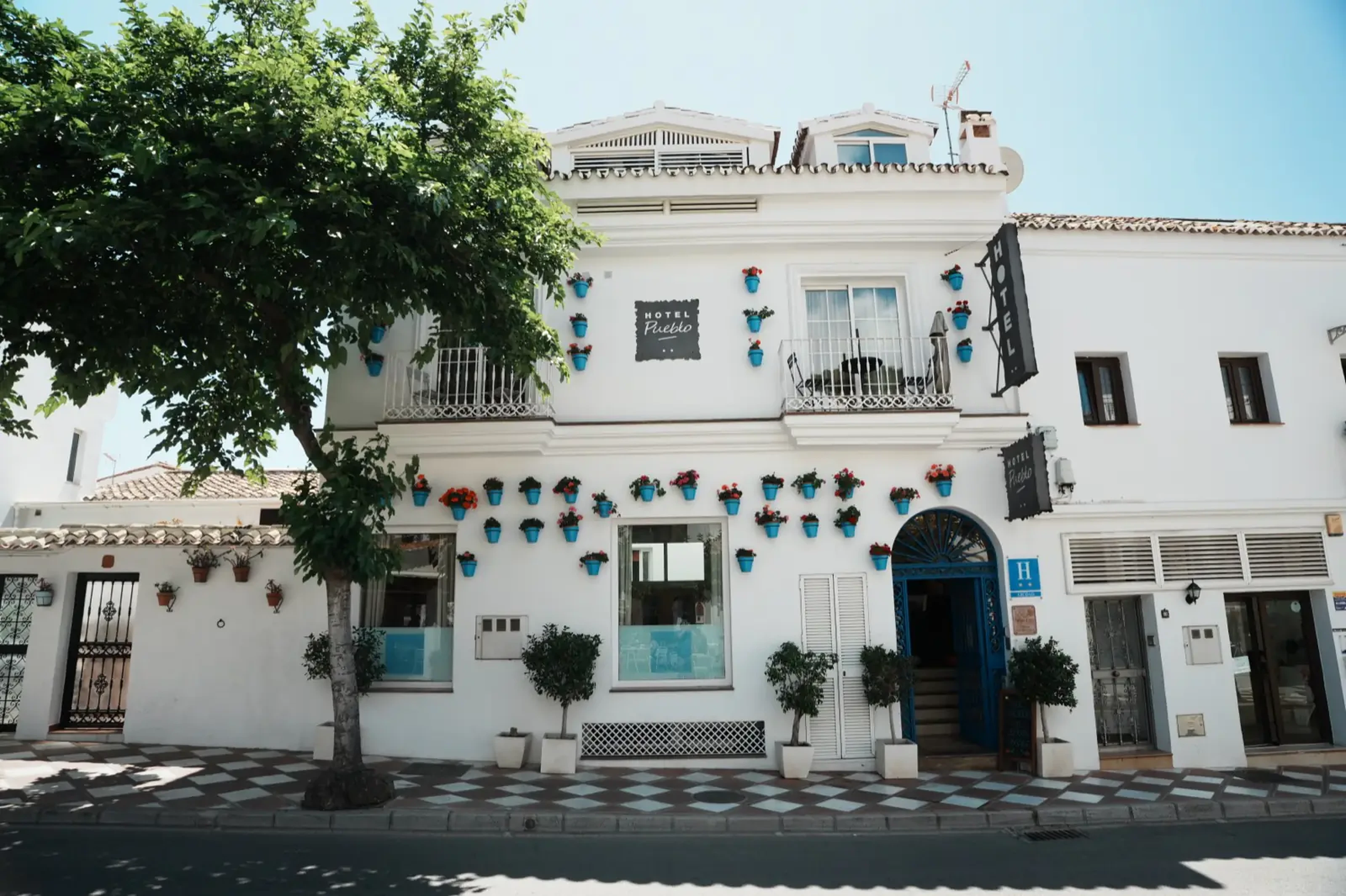Hotel Pueblo facade with blue flower pots on whitewashed walls in Benalmádena