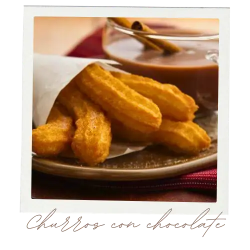 Five churros sticking out of a paper bag on a plate.