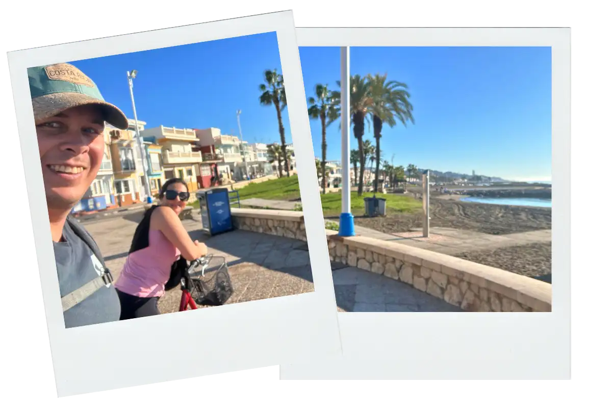 A man and a woman smiling while holding their bicycles.