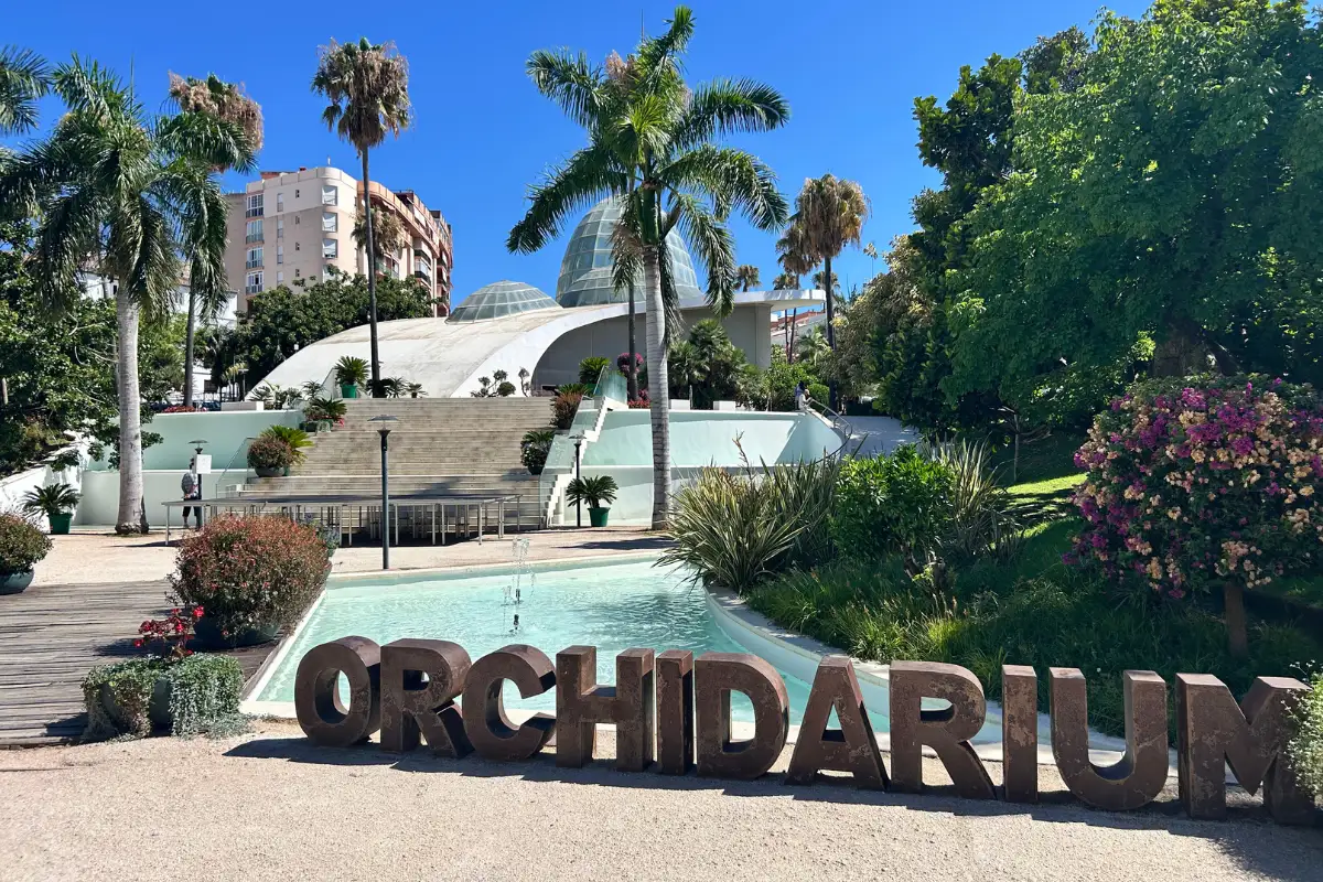 The orchidarium sign with the orchidarium building behind it in Estepona.