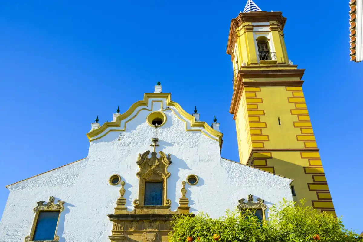 A tall view of a church in Estepona with a blue sky background.