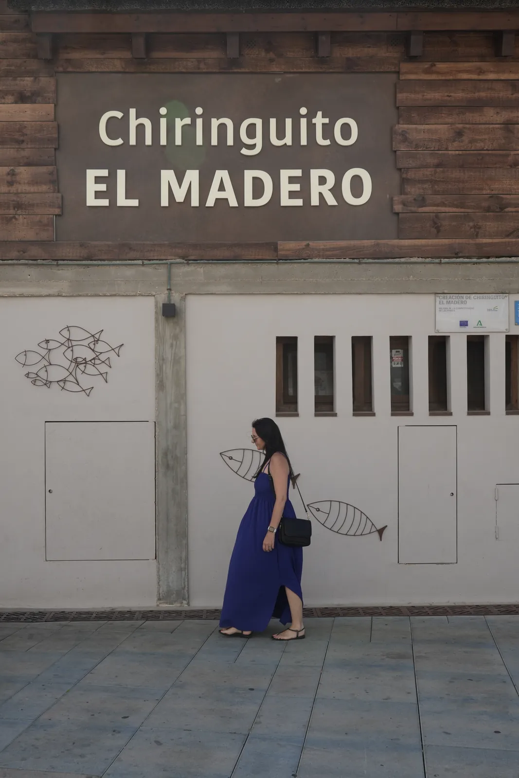 Heidi walking past the Chiringuito El Madero sign on the Estepona beachfront