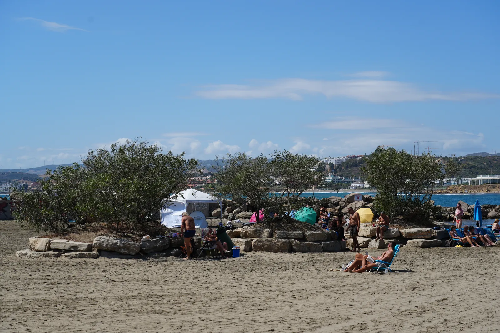 Cove beach backed by rocks with sunbathers in Estepona