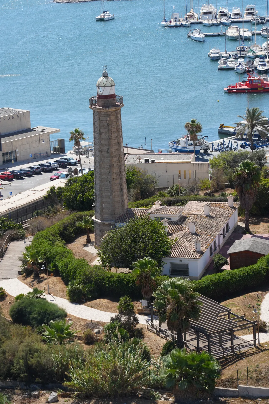 Estepona lighthouse and marina seen from above, boats moored beside the harbour with mountains behind