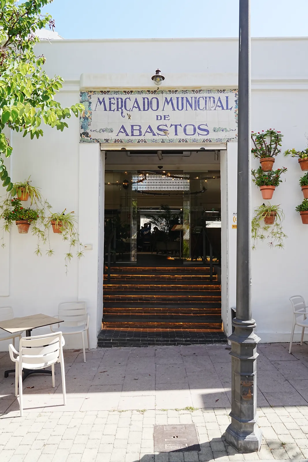 Entrance to the revamped Mercado Municipal de Abastos in Estepona, original tiled sign above a modernised glowing staircase