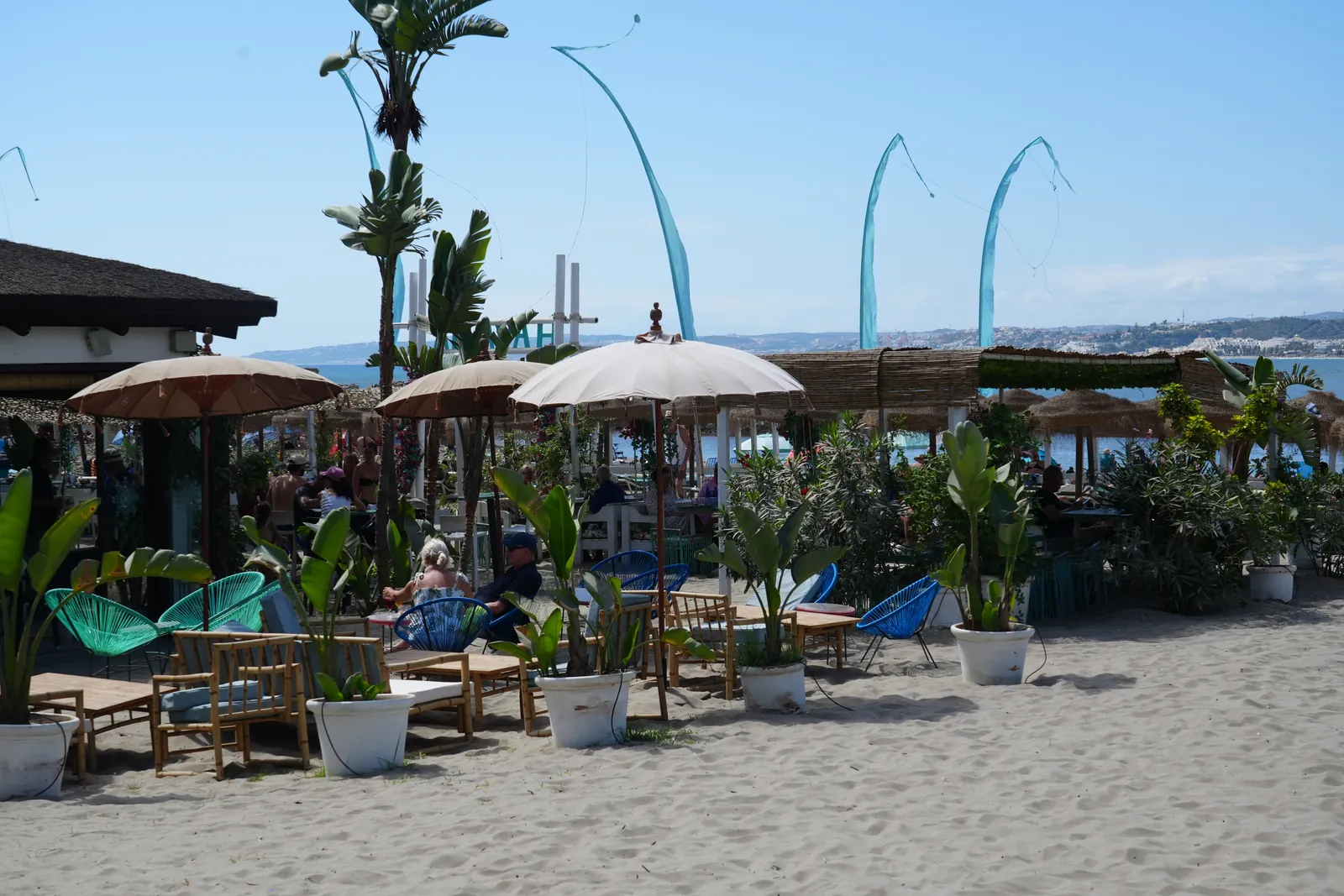 Blue flags and straw parasols on the sand at Havana Beach Club, Playa del Cristo, Estepona