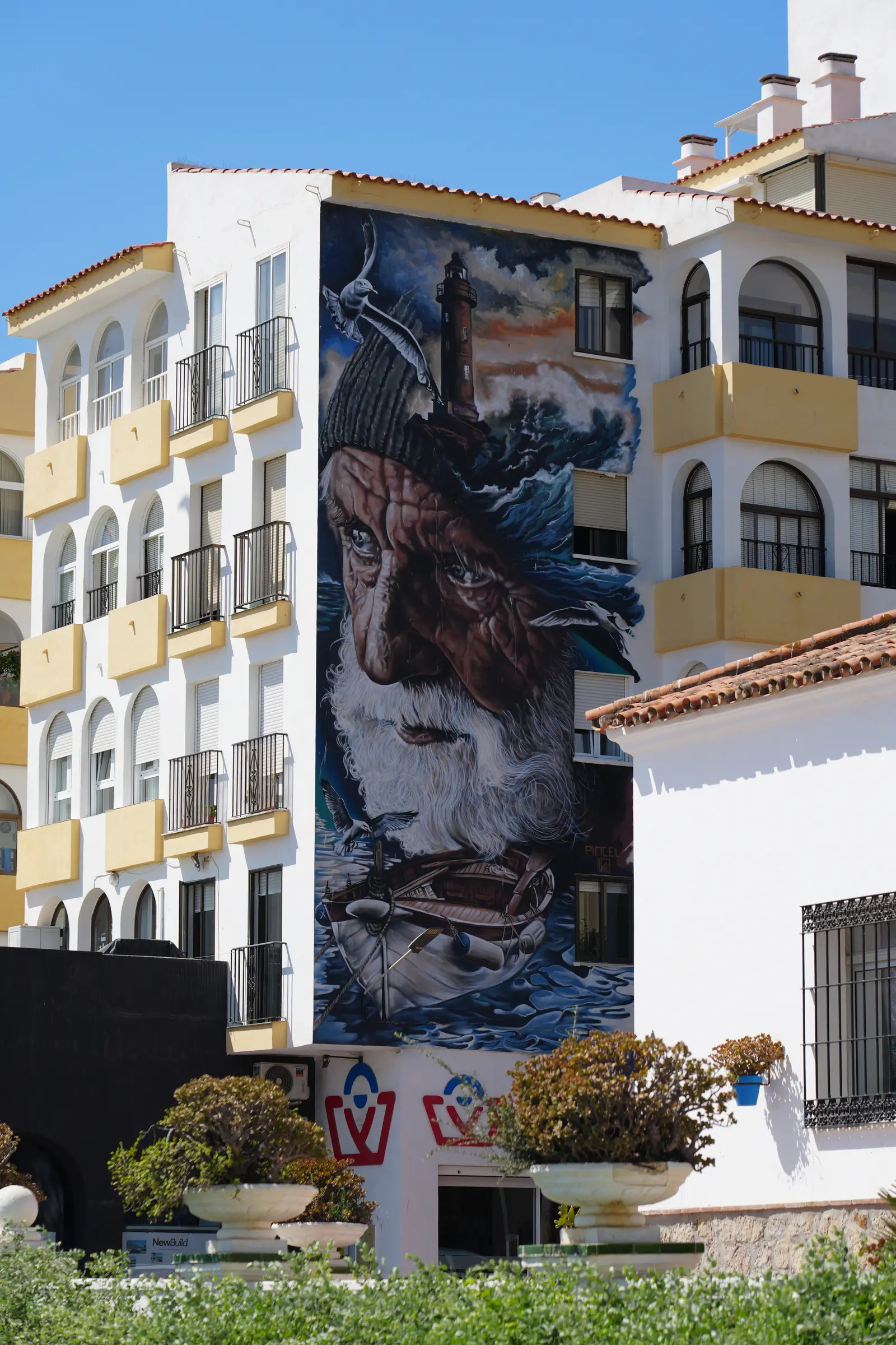 Old fisherman portrait mural with a storm painted into his knit cap in Estepona