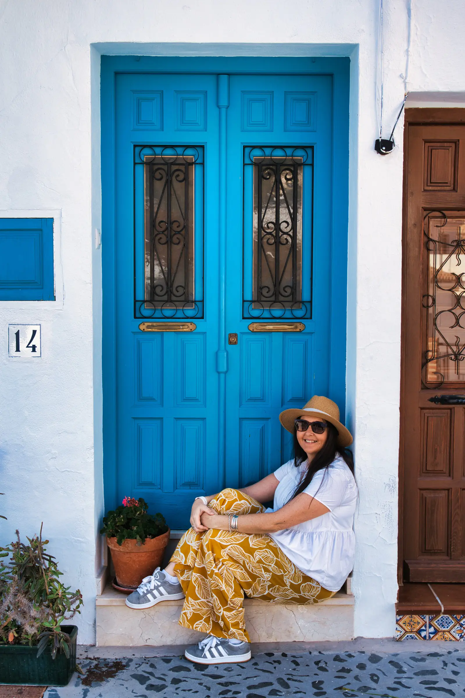 Woman posing by a blue painted door in the whitewashed village of Frigiliana