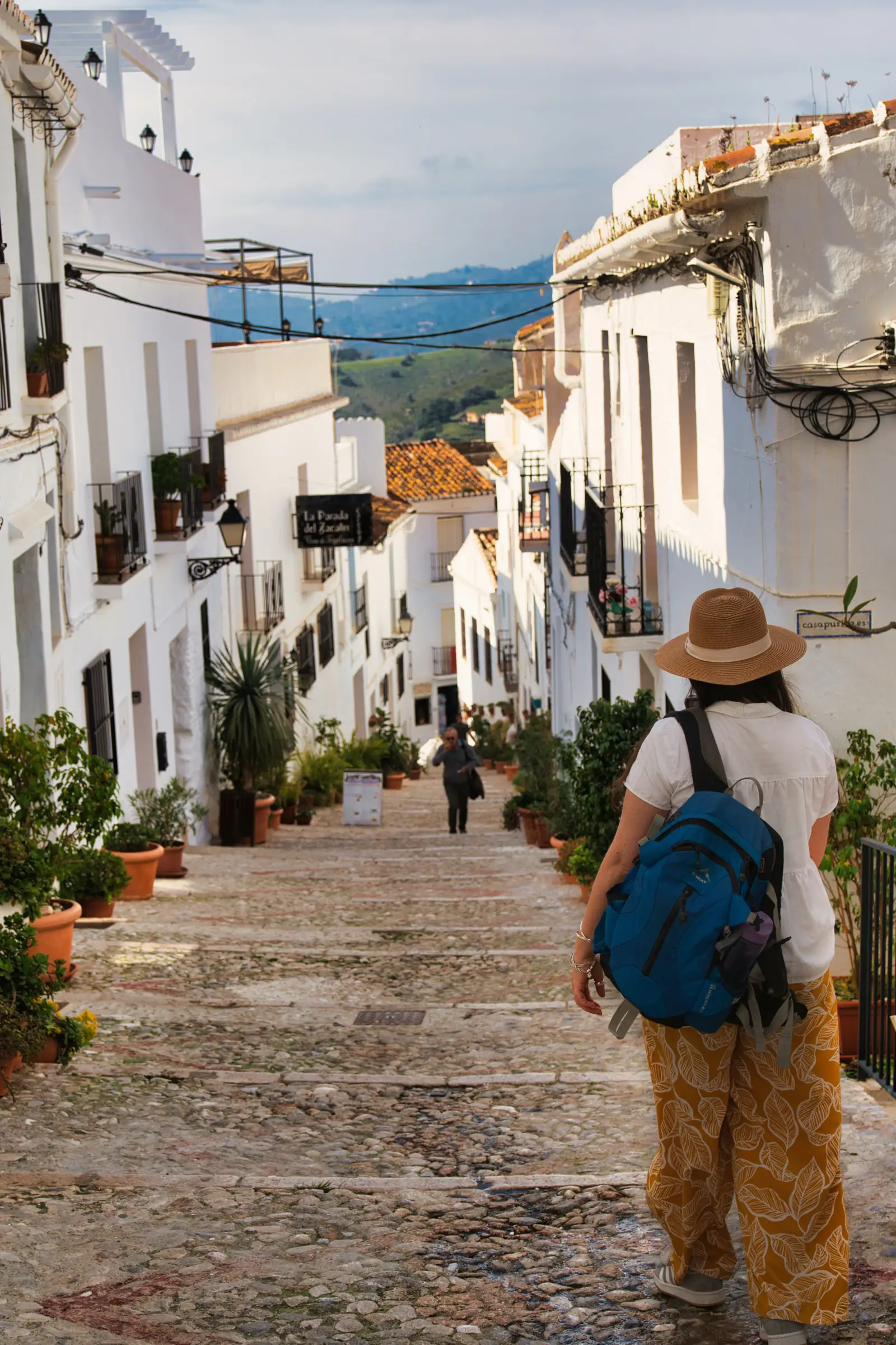 Woman walking up a steep cobbled street in Frigiliana white village