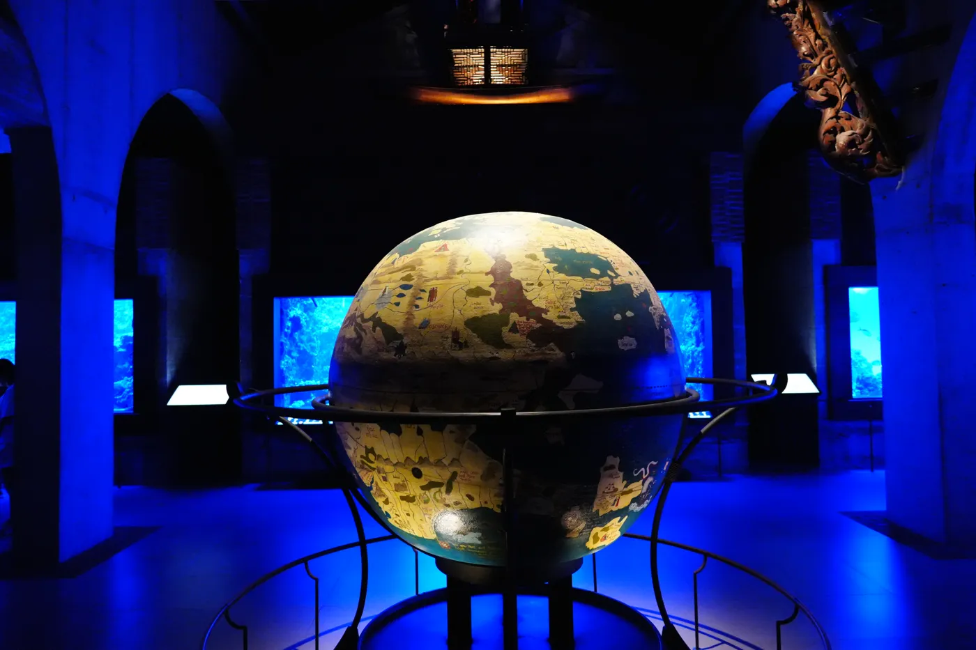The antique globe lit in blue with an old map of the continents, framed by dark stone arches at Bioparc Fuengirola