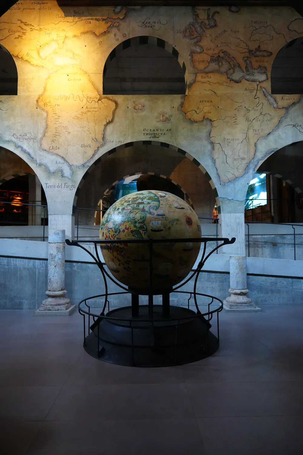 A large antique-style globe on an iron stand in a hall of arches at Bioparc Fuengirola