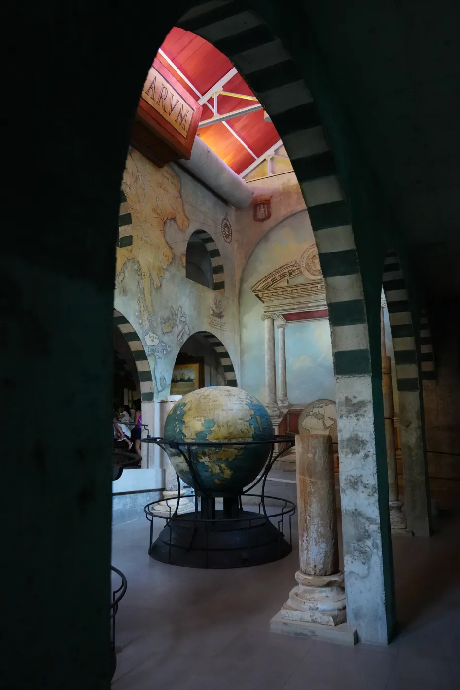 Looking through a black-and-white striped stone arch toward the globe in the explorer hall at Bioparc Fuengirola