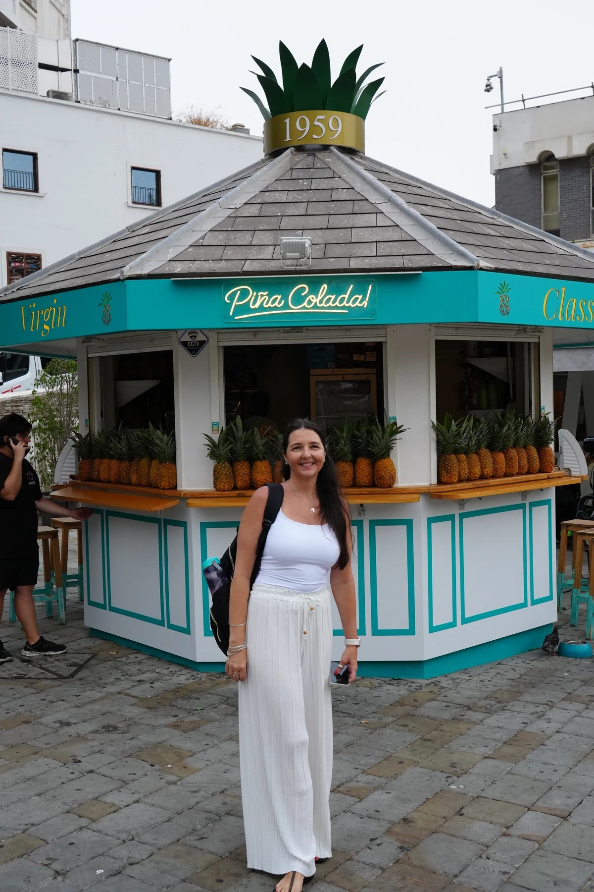 Holding a pina colada served in a pineapple at a kiosk in Gibraltar