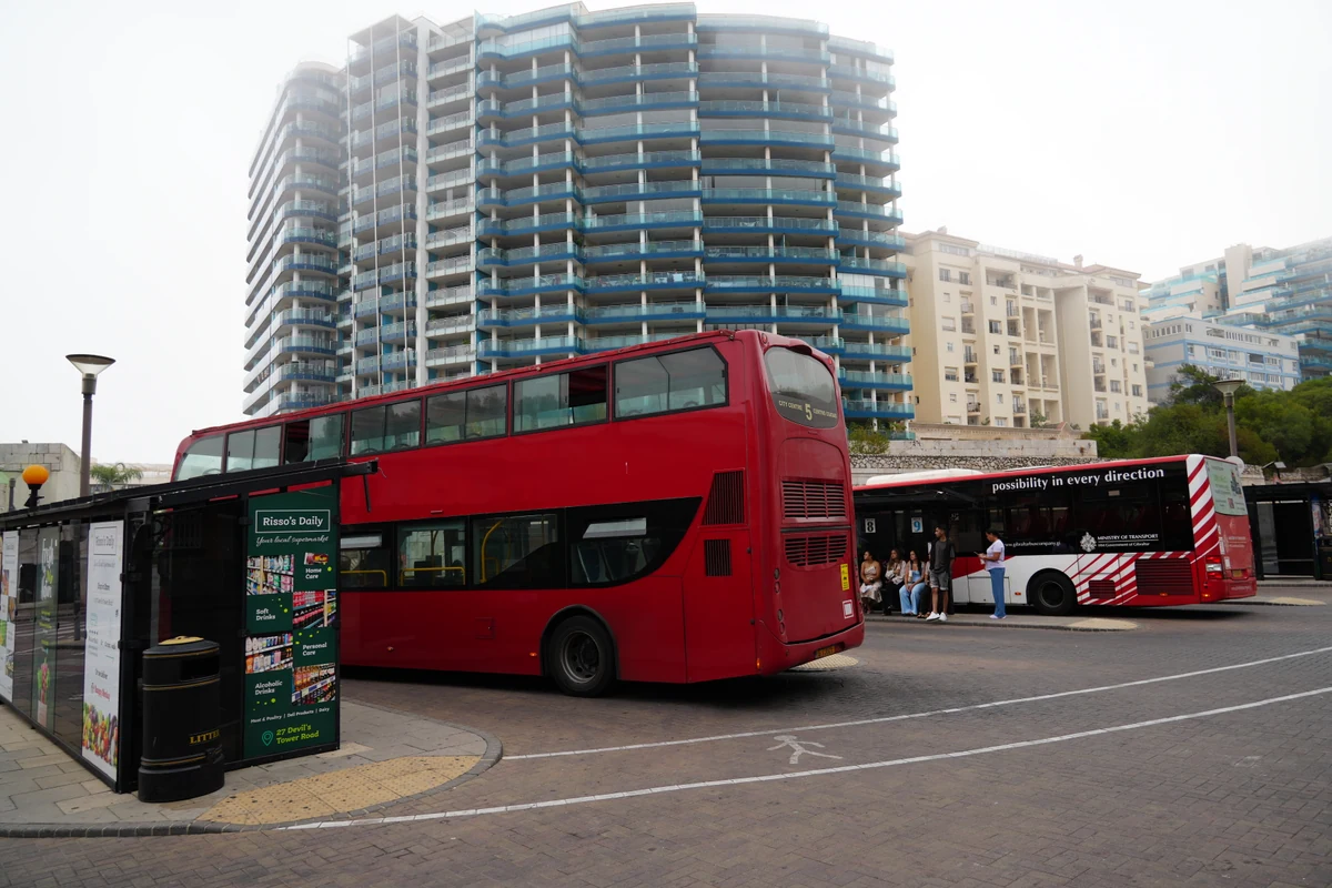 Red double decker bus at the terminus beside Gibraltar's city walls