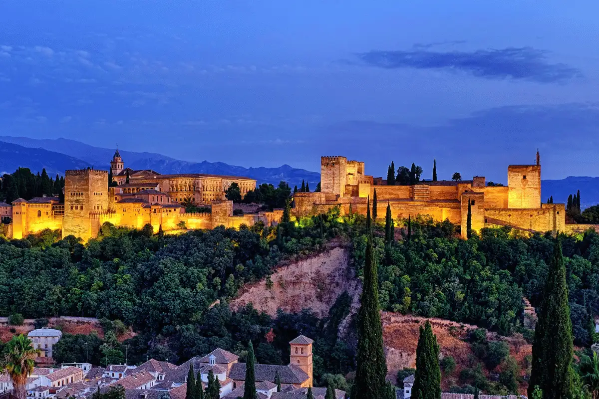 The Alhambra palace illuminated at night, viewed from the Albaicín quarter in Granada