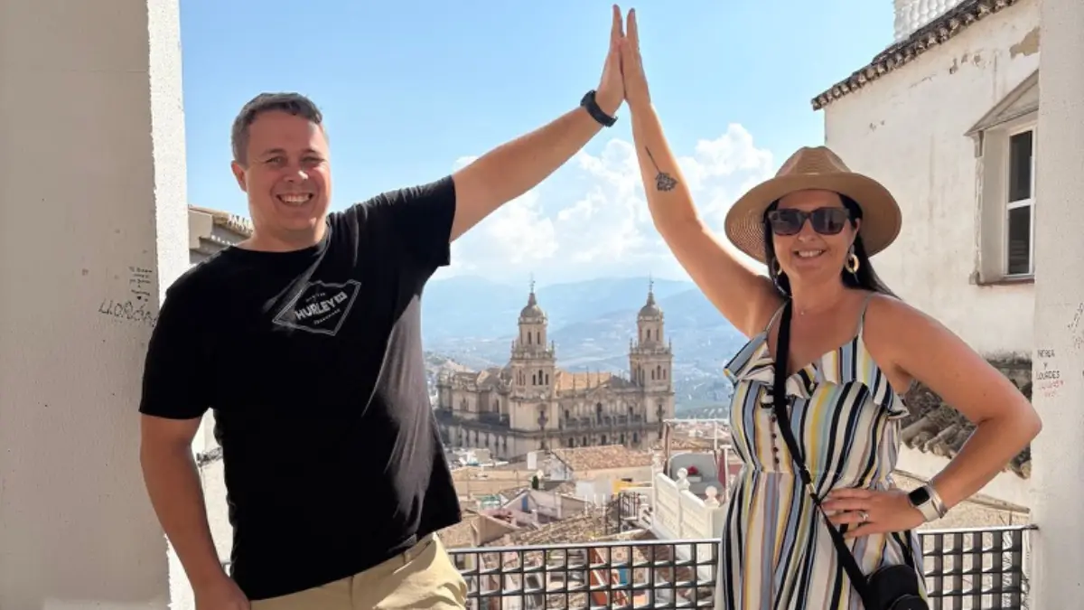 Couple high-fiving on a rooftop viewpoint with Jaén Cathedral in the background