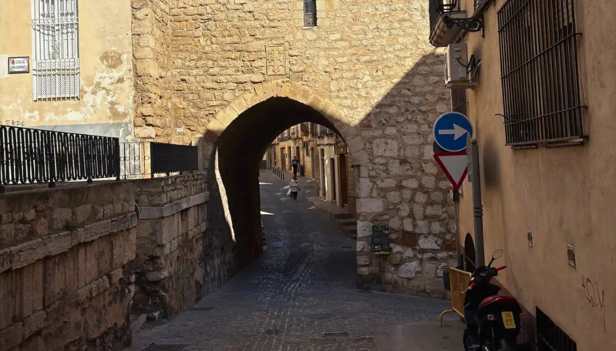 Stone archway in Jaén old town leading to a narrow cobbled street