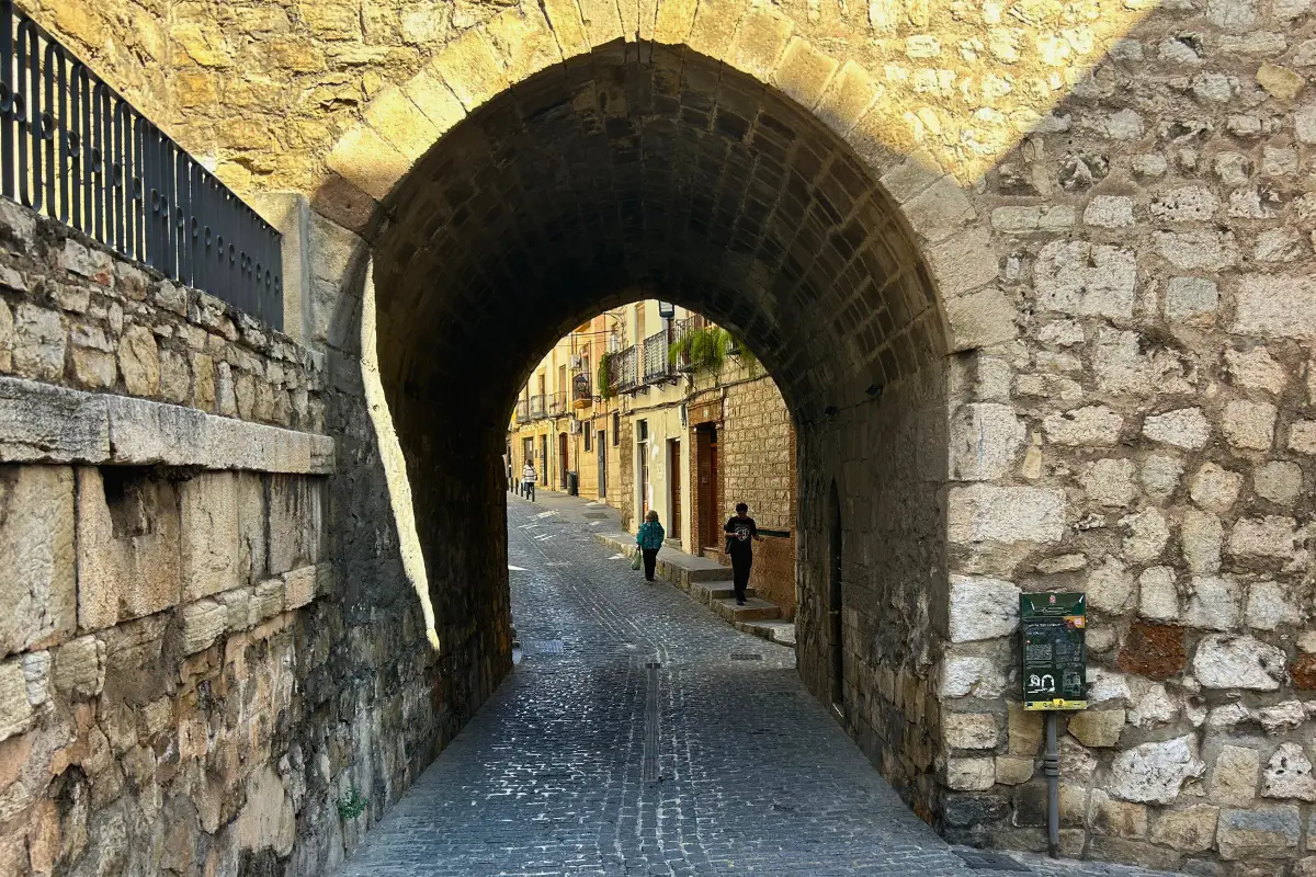 Narrow cobblestone passageway through a medieval stone arch in Jaén old town