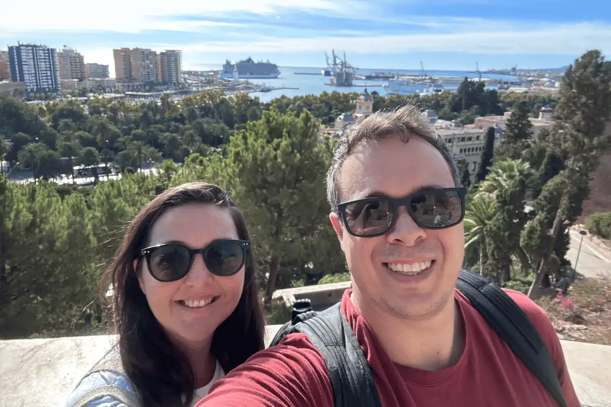 A man and a woman (Jethro and Heidi) taking a self-portrait with the Malaga harbour behind them.